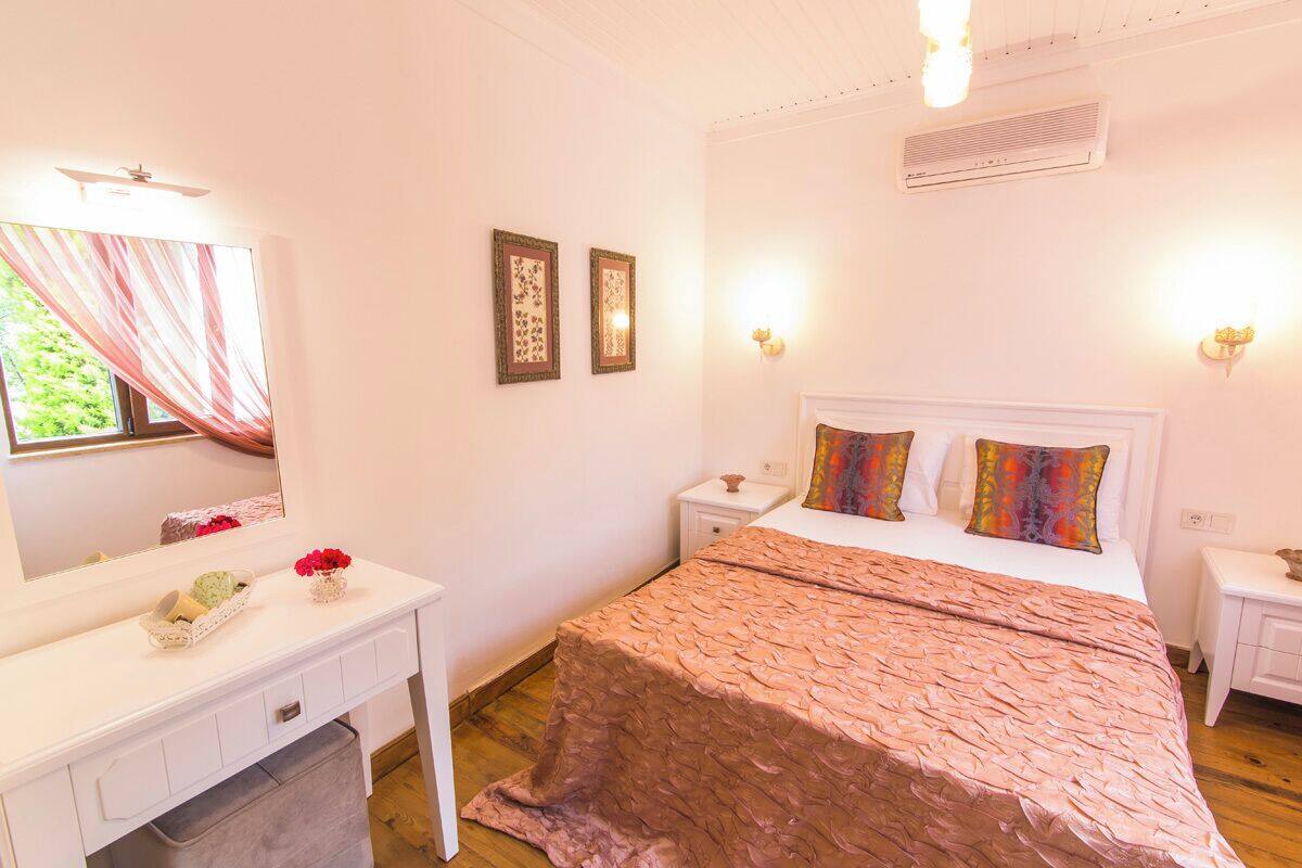A bedroom with a bed, bedside tables, a dresser, a mirror, and wall-mounted lights.