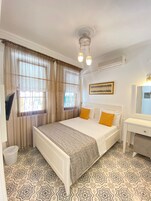 Habitación de hotel con cama, escritorio, televisor y suelo estampado.