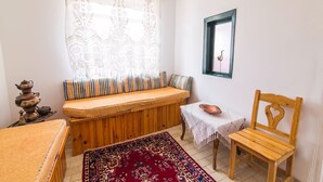 A cozy room with a wooden bench, a small table with a bowl, a chair, a patterned rug, and a decorative lamp. - Bozcaada Butik Pansiyon (Bozcaada)