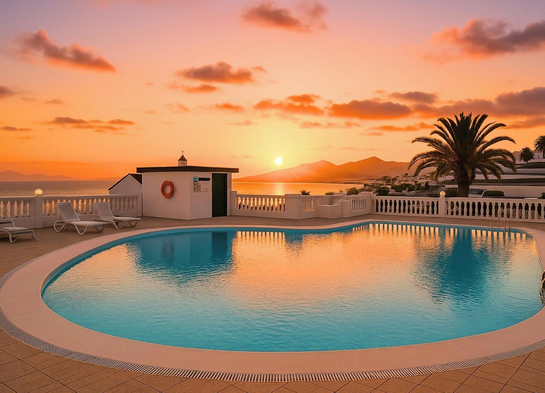 A swimming pool with a view of the sunset and mountains.