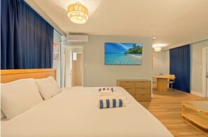 Habitación de hotel con una cama grande, un escritorio, una silla y vistas a una playa.