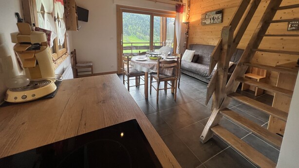 L’intérieur d’un chalet confortable, avec un coin repas, un canapé et un escalier.