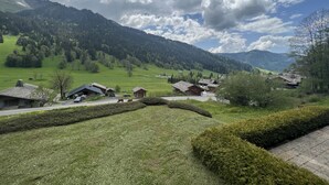 Un village rural avec des maisons traditionnelles en bois, une route sinueuse et un paysage montagneux en toile de fond.