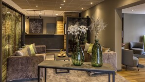 A modern living room with a sofa, armchairs, a coffee table, and decorative vases. - Hotel Imhof (Gemuenden)