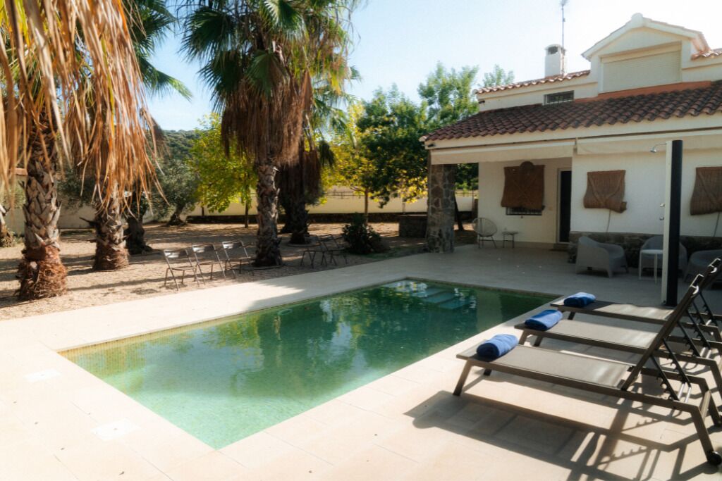 Uma área de piscina com espreguiçadeiras e um terraço coberto.