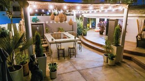 Un patio al aire libre con barra, asientos y plantas en macetas.