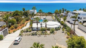 Una propiedad costera con piscina, palmeras y vistas al mar.