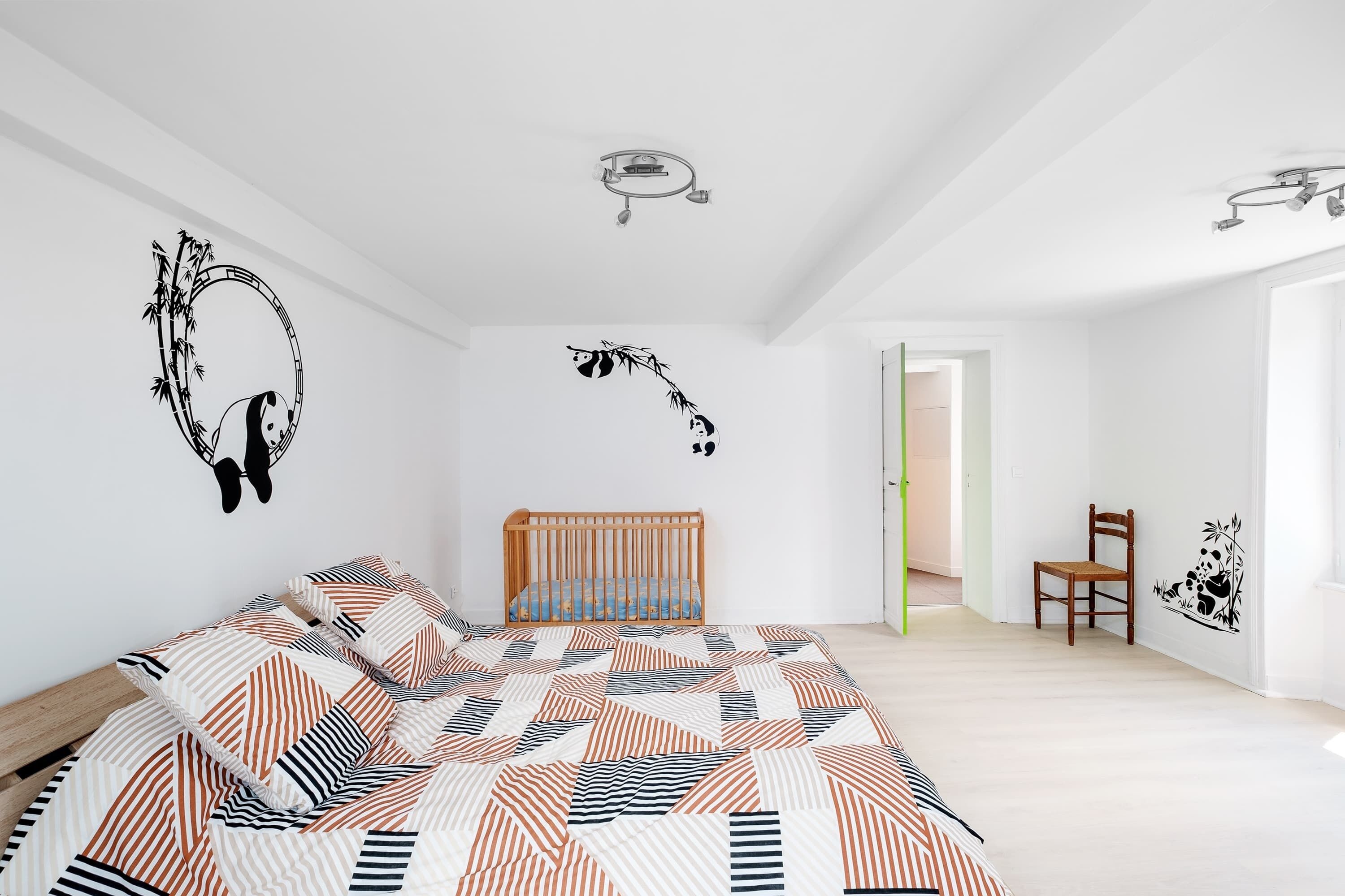 Une chambre à coucher avec un lit, un berceau et une chaise.