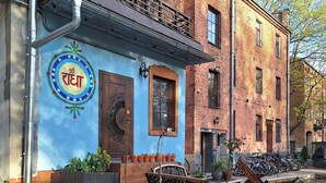 Un edificio con fachada azul, puerta de madera y una banca en el exterior.