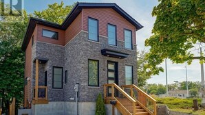 A modern two-story house with a stone facade, large windows, and a wooden staircase. - Near Ridley College  (St. Catharines)