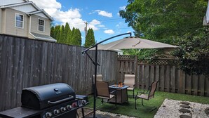 A backyard with a grill, outdoor seating, a pergola, and a wooden fence. - Modern Retreat near Top Golf (Hilsboro)