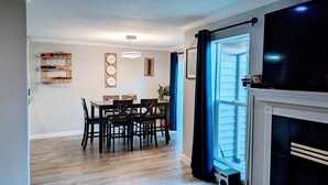 A dining area with a table and chairs, a ceiling light, and a wall with decorative items. - Modern Retreat near Top Golf (Hilsboro)