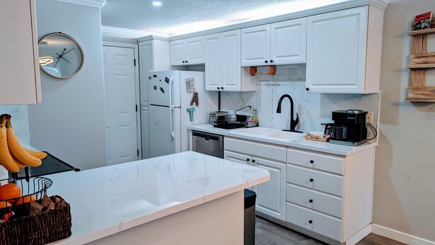 A modern kitchen with white cabinets, a black coffee maker, and a fruit basket. - Modern Retreat near Top Golf (Hilsboro)