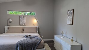 A bedroom with a bed, bedside lamp, window, and artwork on the wall. - Modern Retreat near Top Golf (Hilsboro)