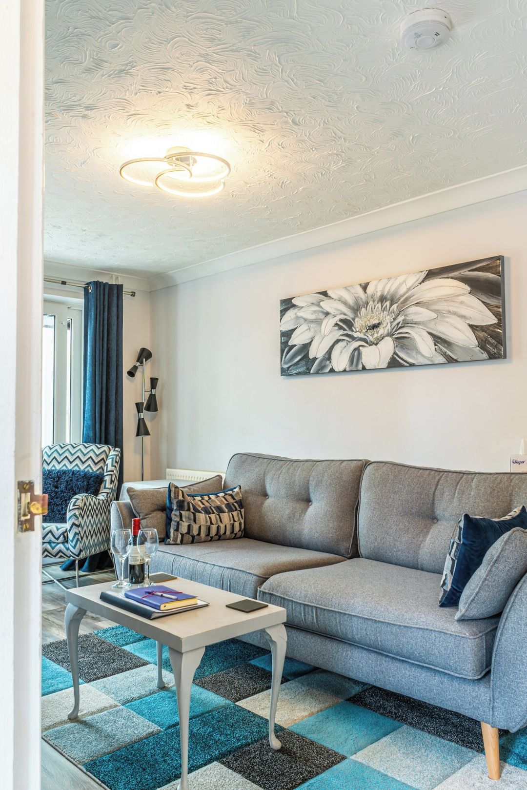 A living room with a grey sofa, a coffee table, and a patterned rug.