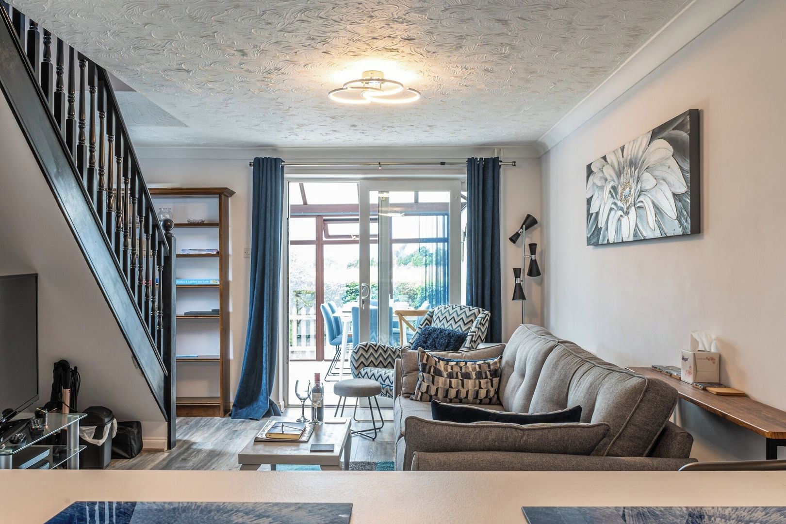 Un salon moderne avec un escalier, un coin repas et une vue à travers des portes vitrées.