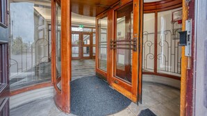 A hotel entrance with wooden doors, a black doormat, and a metal gate. - The Post House Two by Fortuna Property Portfolio, The Post House Two Apartment (Gloucester District)