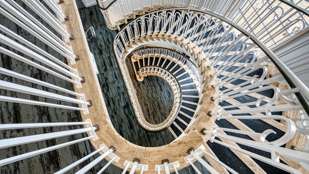 A spiral staircase with white railings and a central wooden handrail. - The Post House Two by Fortuna Property Portfolio, The Post House Two Apartment (Gloucester District)