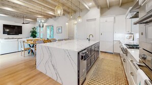 Una cocina moderna con una isla de mármol, electrodomésticos de acero inoxidable e iluminación colgante.