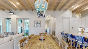 Un comedor amplio con una mesa y sillas de madera, un candelabro y vistas al exterior.