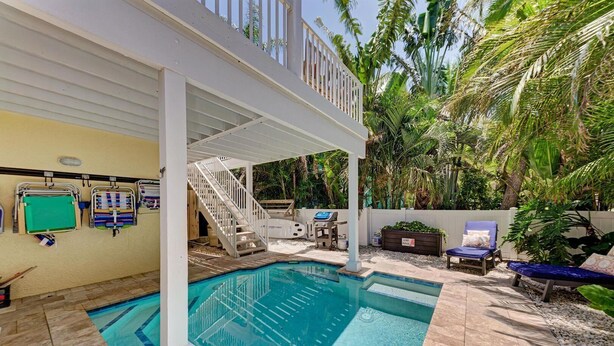 Une piscine dotée d’un espace couvert, de chaises longues et d’un barbecue.