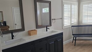 Une salle de bain avec un grand miroir, un lavabo et un banc.