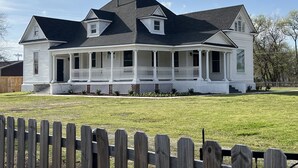 A two-story house with a wrap-around porch, a gabled roof, and a chimney. - Plenty of space to relax! Near Turner falls, the lake & Crossbar Ranch. Sleeps 6 (Davis)