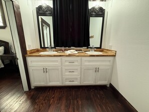 A bathroom with a double sink vanity, wooden countertop, white cabinets, and a large mirror. - Plenty of space to relax! Near Turner falls, the lake & Crossbar Ranch. Sleeps 6 (Davis)