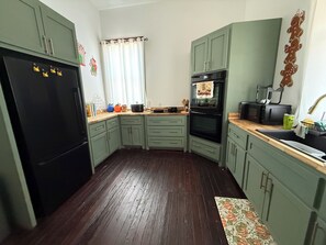 A kitchen with green cabinets, a black refrigerator, a microwave, and a stove. - Plenty of space to relax! Near Turner falls, the lake & Crossbar Ranch. Sleeps 6 (Davis)