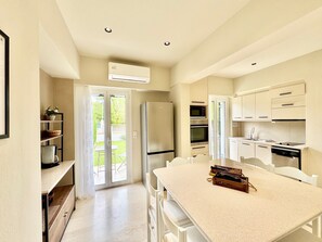 A modern kitchen with a central island, built-in appliances, and a sliding glass door leading to a patio.