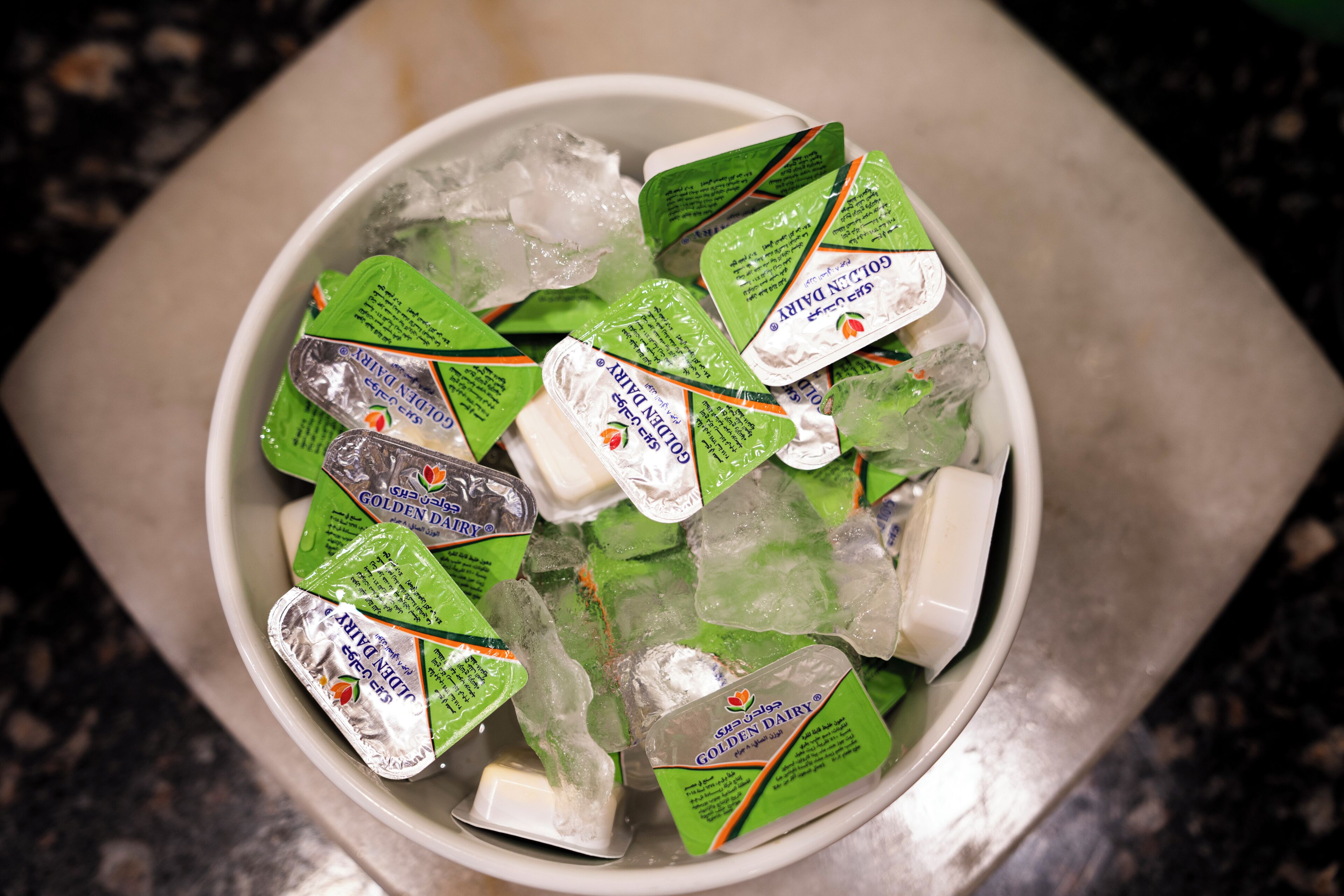 A bowl containing ice and several packets of Golden Dairy ice cream.