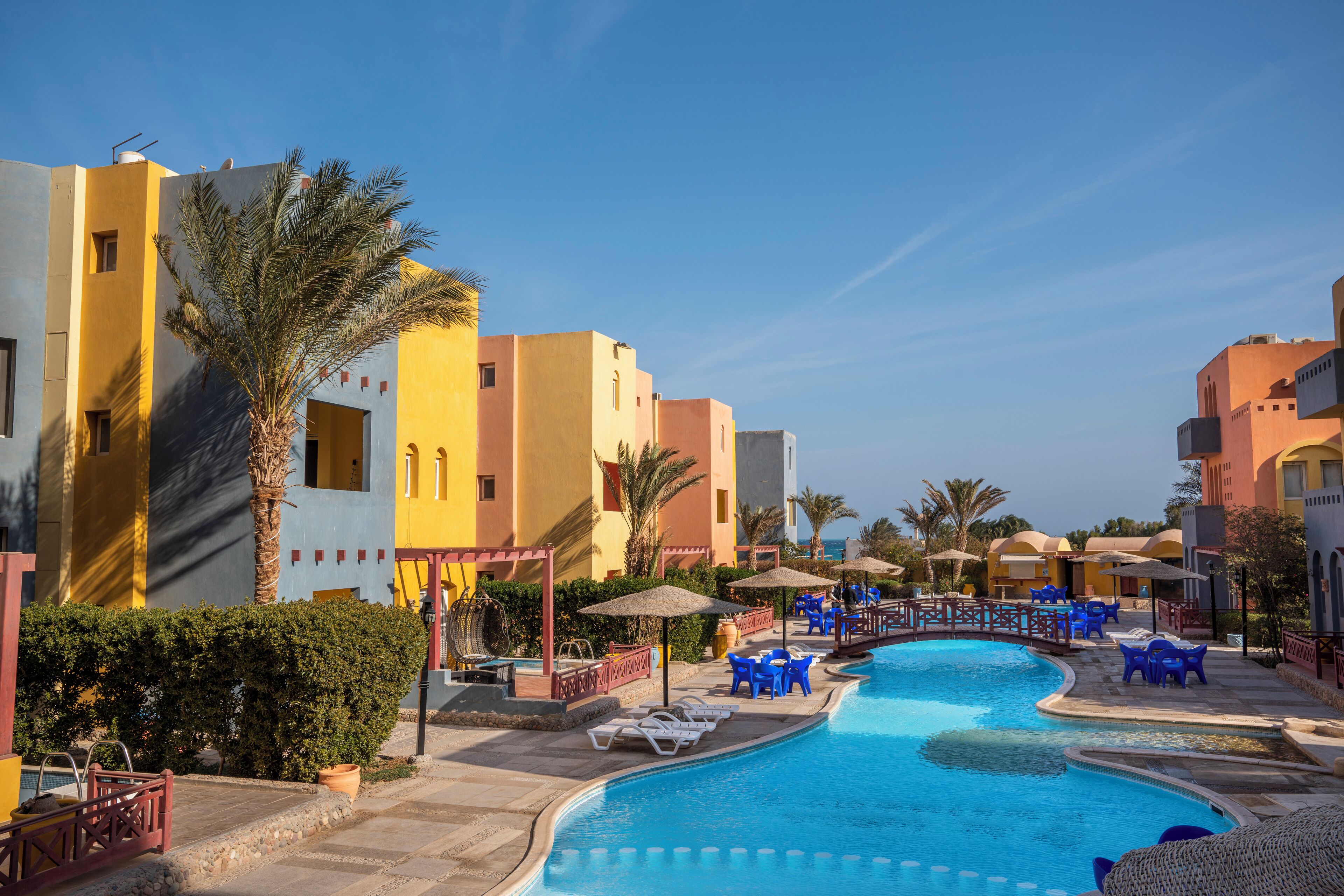 A resort with a swimming pool, palm trees, and colorful buildings.