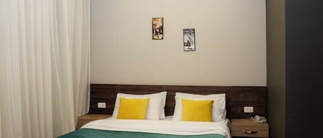 Una habitación de hotel moderna con una cama de madera, ropa de cama blanca y una mesita de noche con un teléfono.