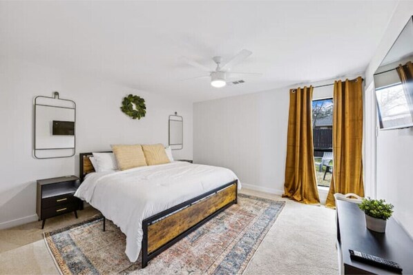A bedroom with a bed, nightstands, a ceiling fan, a window with curtains, and a small table with a plant. - Frisco Caddy Shack
(Frisco)
