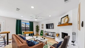 Una sala de estar con chimenea, sofá, mesa de centro y televisor montado en la pared.