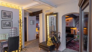 Un intérieur chaleureux avec une cheminée, un coin salon et un couloir agrémenté d’œuvres d’art encadrées.