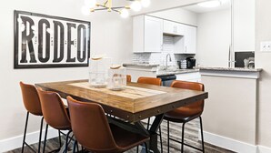 Une cuisine moderne avec des meubles blancs, une table à manger en bois et des chaises orange.