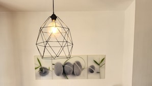 A kitchenette with a coffee maker, toaster, and microwave on a wooden counter, a hanging light fixture, and a wall-mounted decoration of rocks and leaves. - Elegant Studio in Cergy (Cergy)