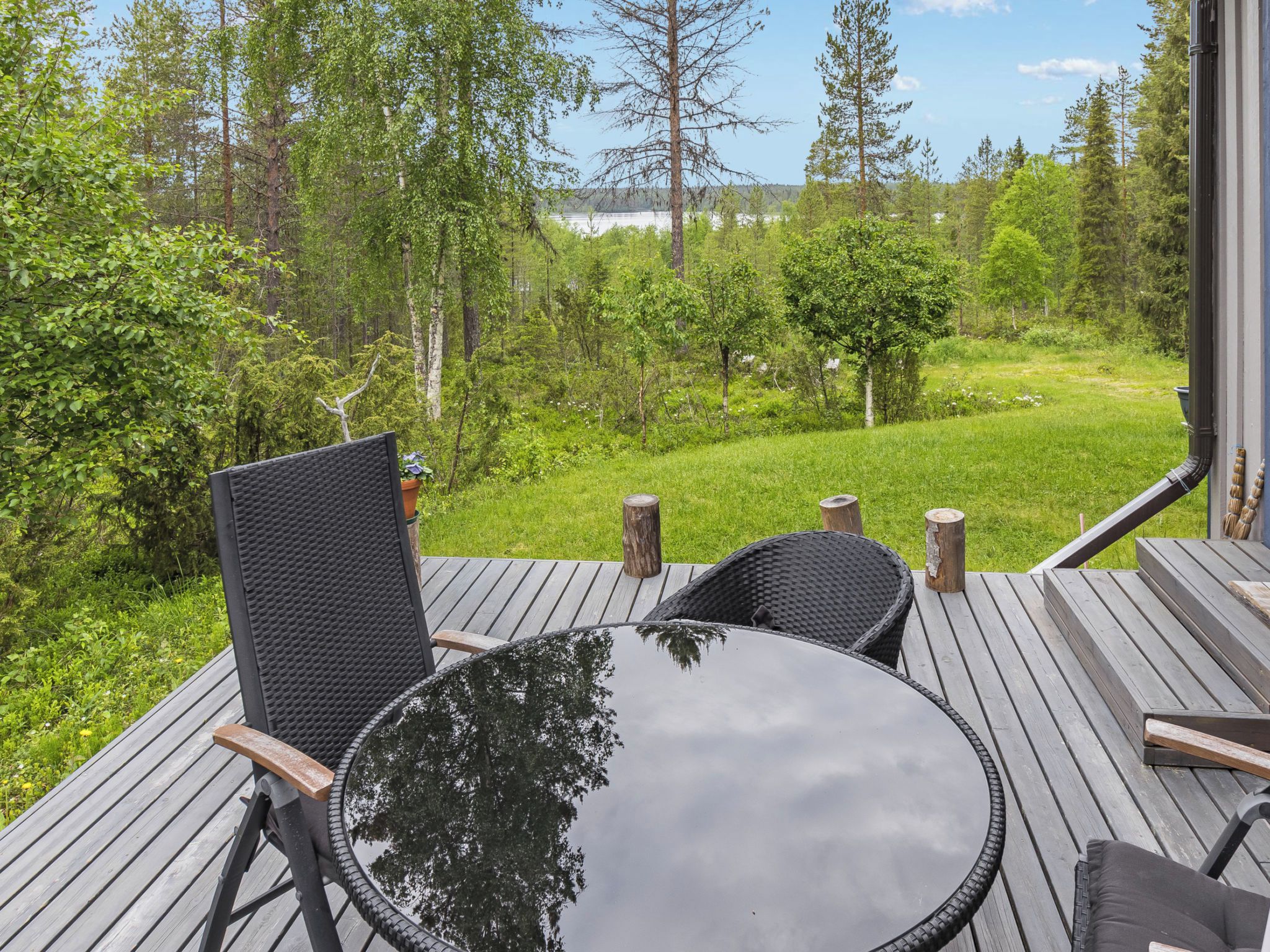Une terrasse extérieure avec une table ronde et des chaises, entourée d’un paysage verdoyant et luxuriant ainsi que d’arbres.