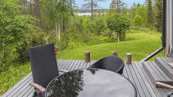 Une terrasse extérieure avec une table ronde et des chaises, entourée d’un paysage verdoyant et luxuriant ainsi que d’arbres.