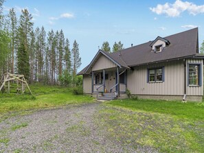 A two-story house with a porch, a gravel driveway, and a forest in the background. - Mustikka by Interhome (Kuusamo)