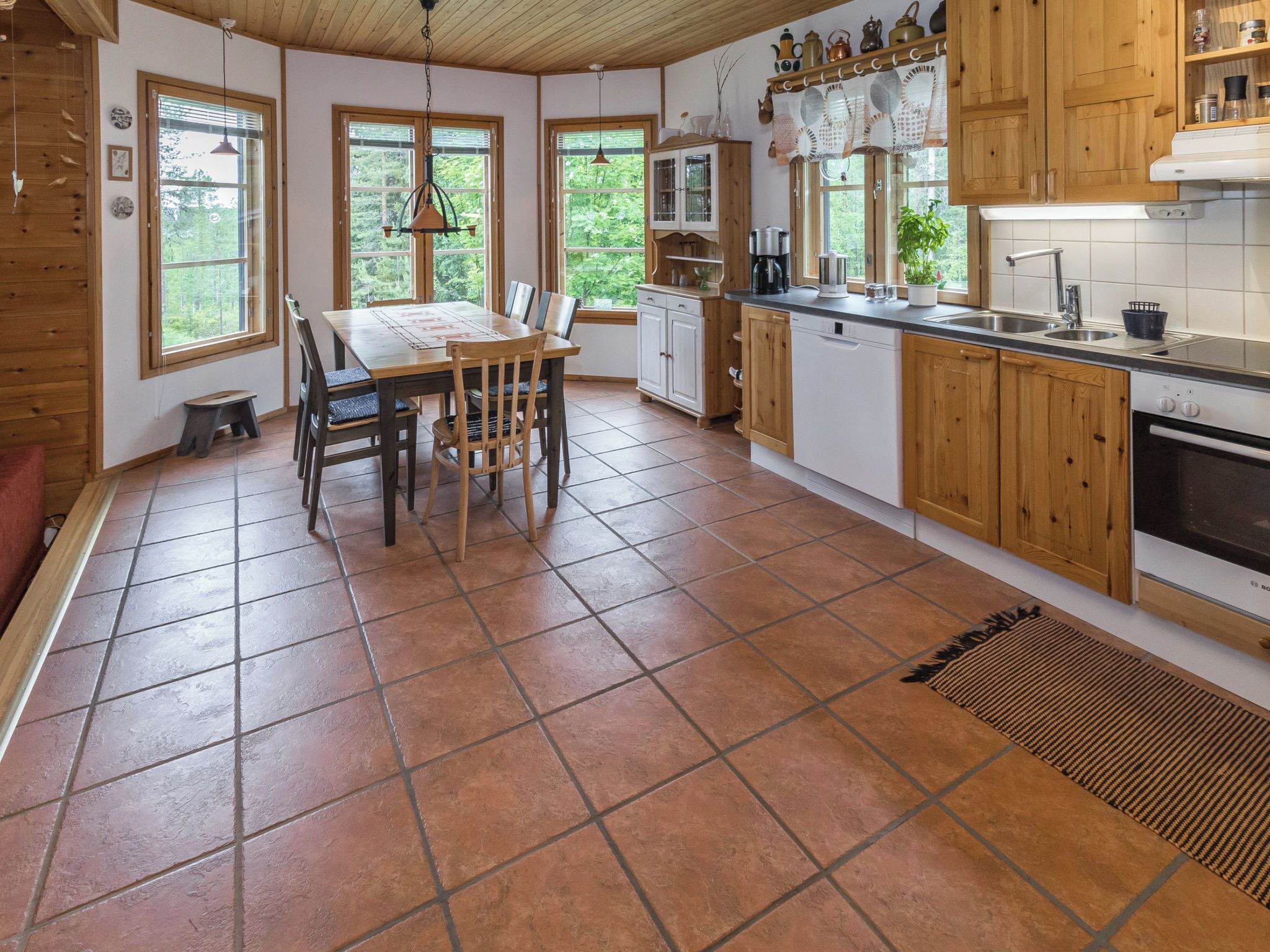 A kitchen with a dining table, chairs, and a sink.