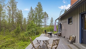 A wooden deck with outdoor furniture, a small table, and chairs. - Mustikka by Interhome (Kuusamo)
