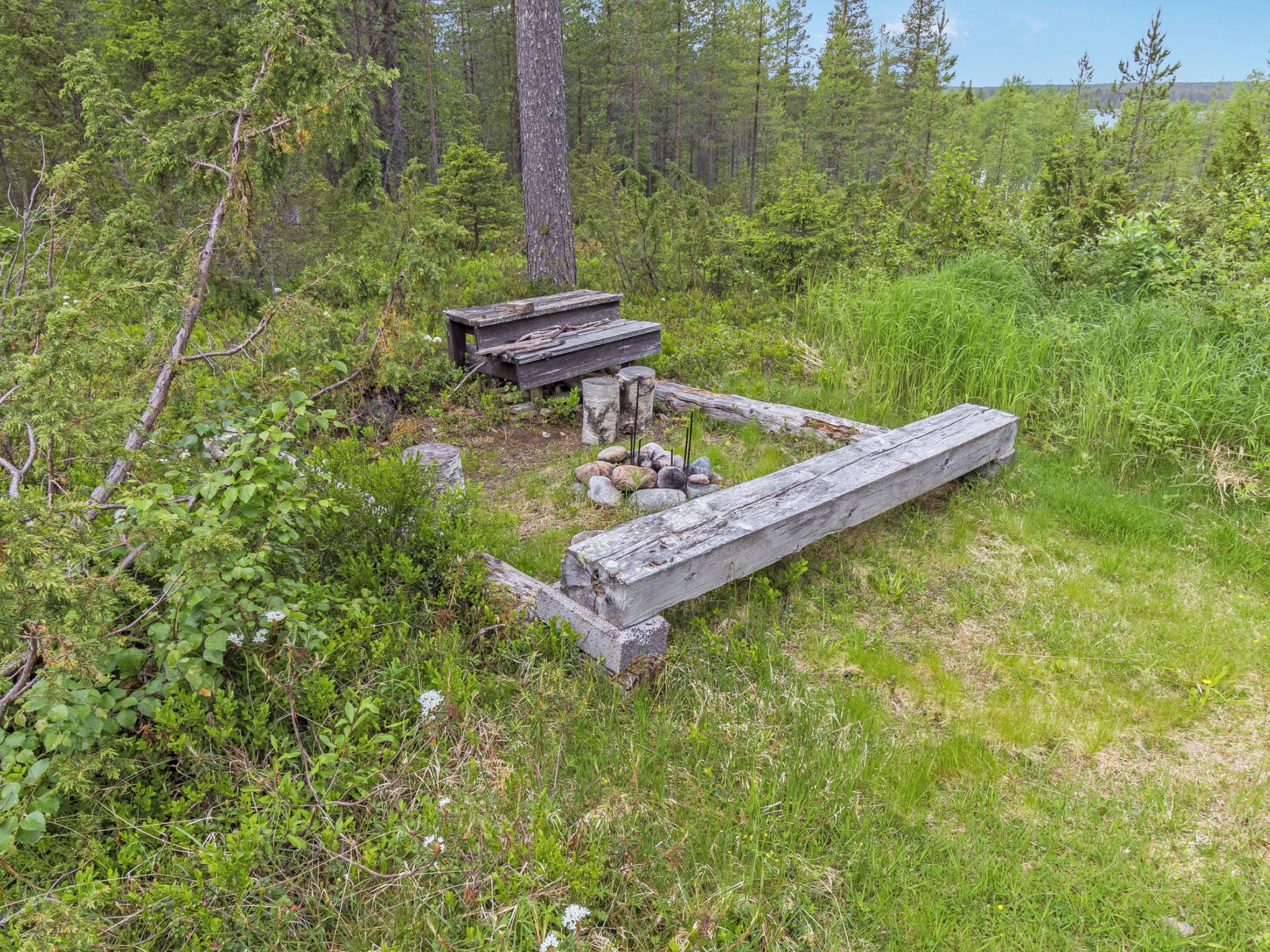 A rustic wooden structure in a forested area with a bench and a table.