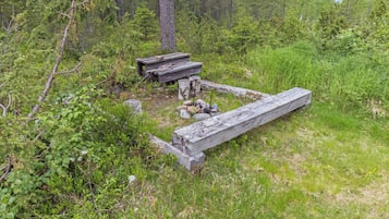 A rustic wooden structure in a forested area with a bench and a table.