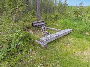 A rustic wooden structure in a forested area with a bench and a table. - Mustikka by Interhome (Kuusamo)