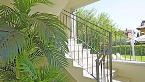 Un escalier avec une rampe en métal, entouré de verdure et offrant une vue sur une maison.