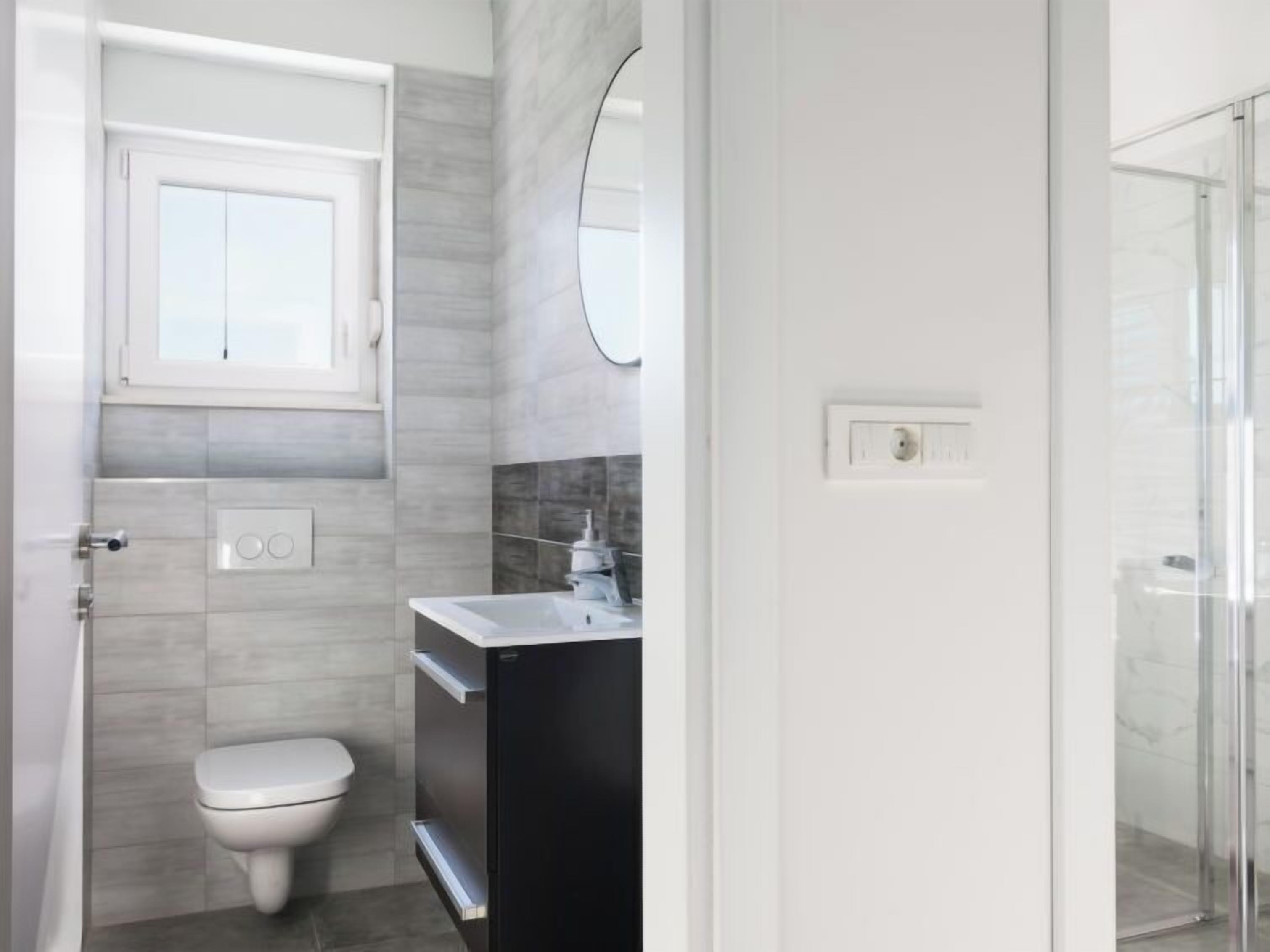 A modern bathroom with a toilet, sink, and shower.