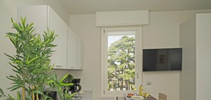 Enjoy meals in the kitchen with a stove and dining area overlooking a balcony with lush greenery.