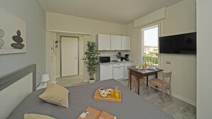 Une chambre d’hôtel de taille réduite, comprenant un lit, une table de chevet et une petite kitchenette.